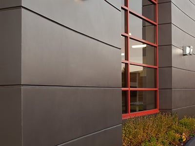 Exterior of a building with gray metallic ReflectIt finish and red window frames