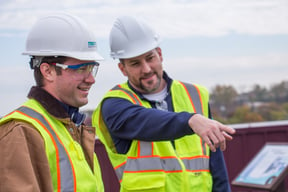 Two construction workers look at project