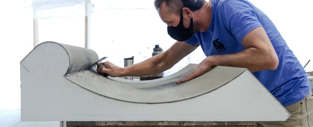 A man in a blue shirt and black mask working on a modular EIFS panel.