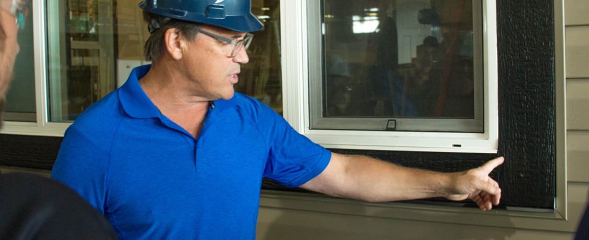 Man points to window components in a factory