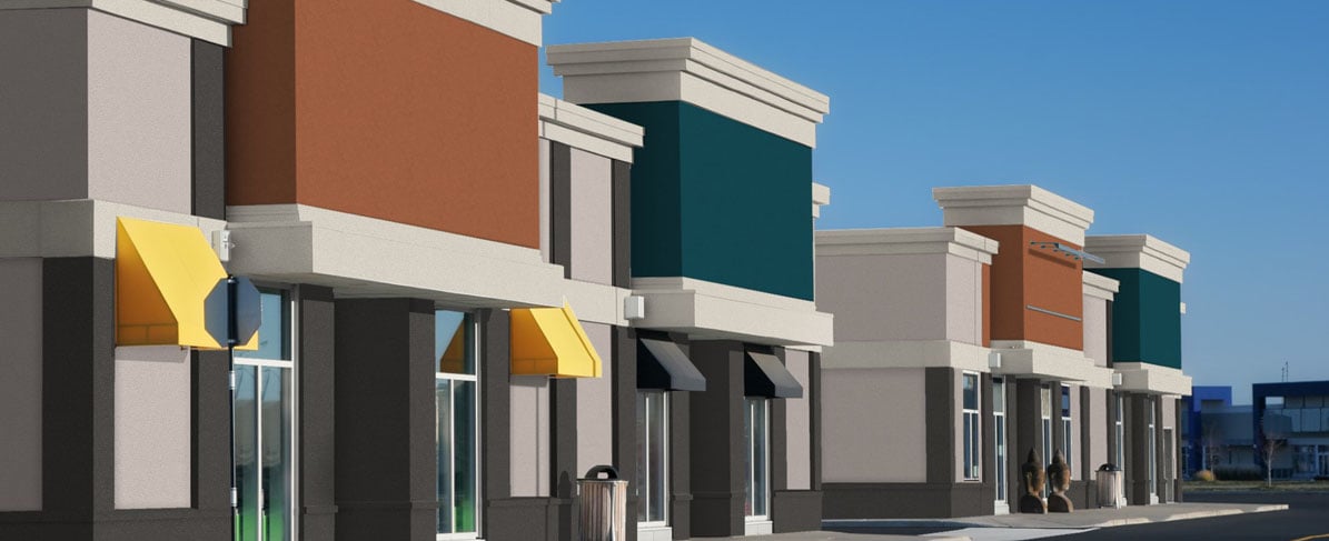 Exterior of retail mall with orange, teal, and gray finishes. 